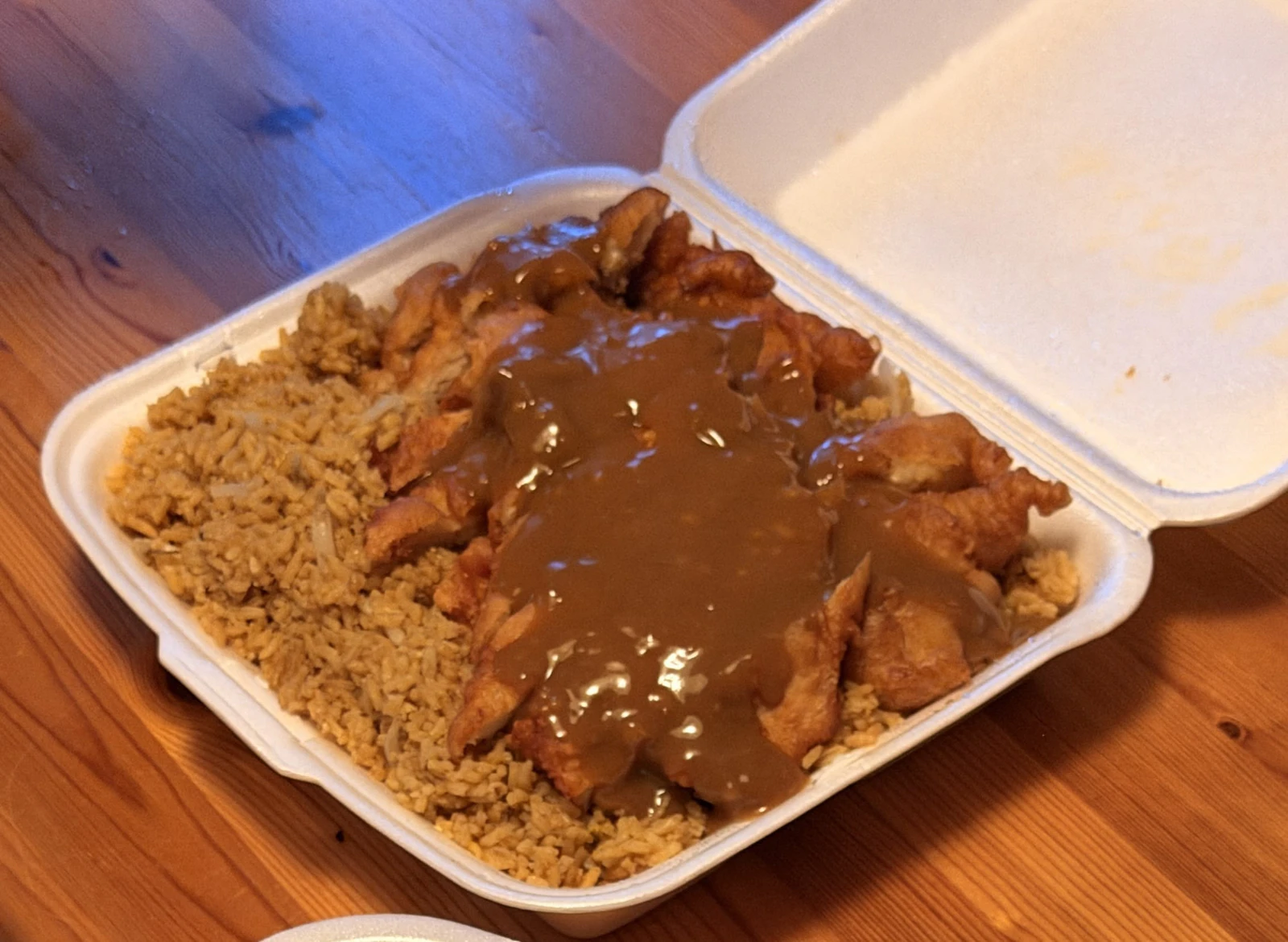 Almond boneless chicken and fried rice in an open takeout container.