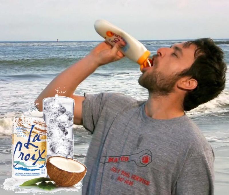 A man on a beach drinks from a lotion bottle beside a Coconut LaCroix can and coconut.