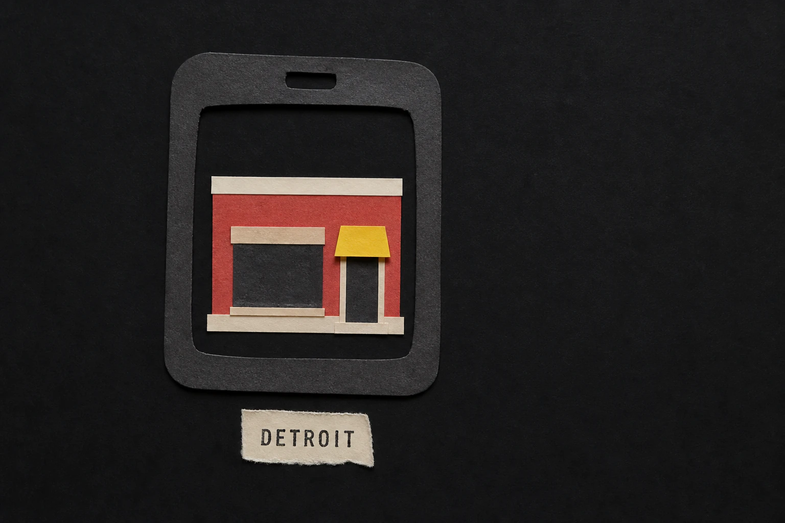 A handmade paper phone frames a red storefront above a torn label reading Detroit.
