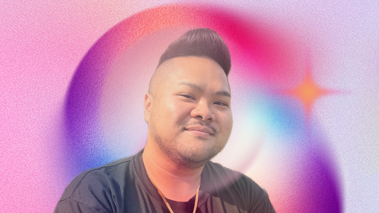 RV Mendoza smiles against a soft pink, purple, and blue abstract background.