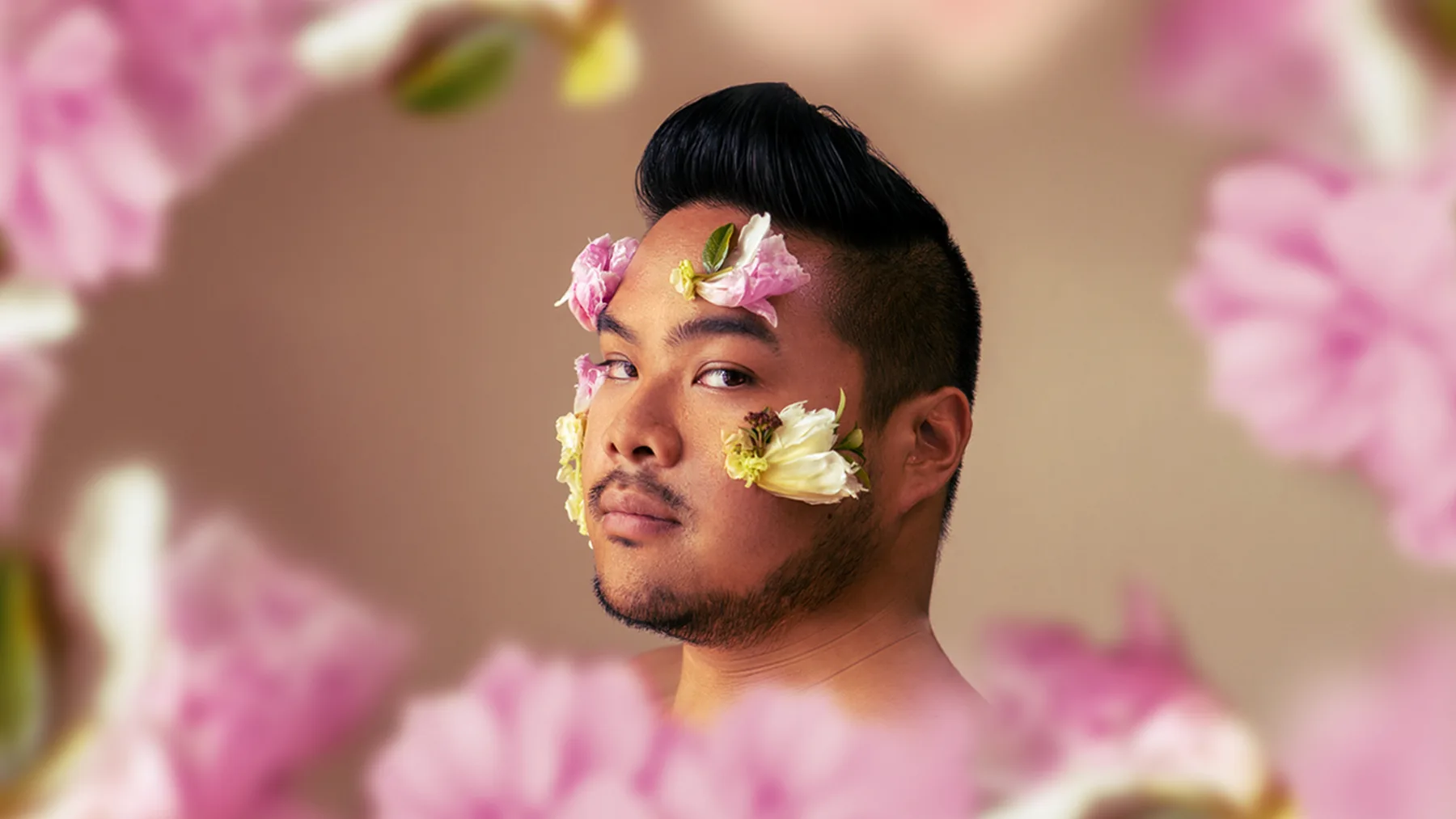 RV Mendoza framed by pink flowers, with blossoms arranged across his face.