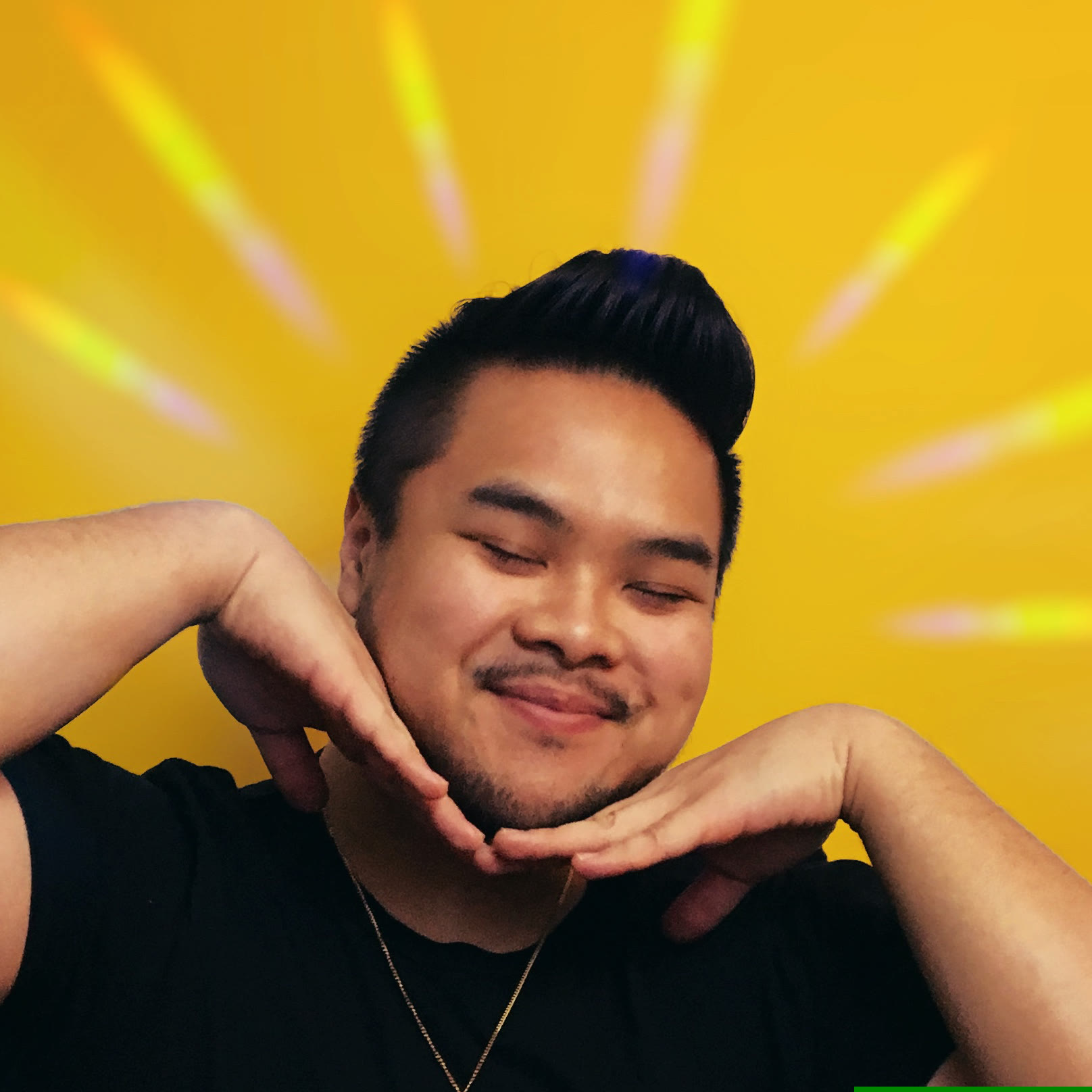 RV Mendoza smiling with his chin resting on his hands against a bright yellow background.